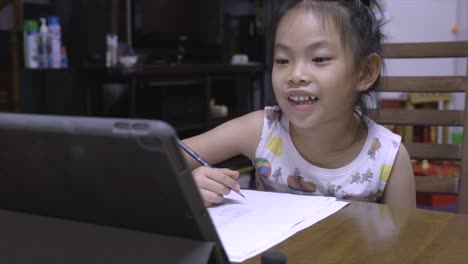 A-little-child-girl-studies-e-learning-from-school-at-home,-using-tablet-to-learn-academic-lessons-online