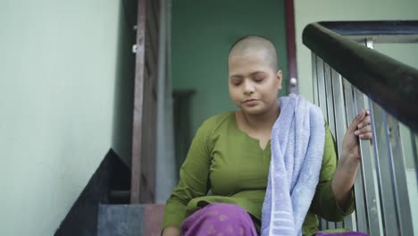 Weak-and-sick-bald-Indian-girl-suffering-from-Cancer,-is-tired-and-sits-on-stairs-panting