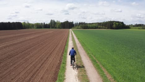 Man-riding-an-e-bike-on-a-straight-dirt-road-on-a-sunny-day