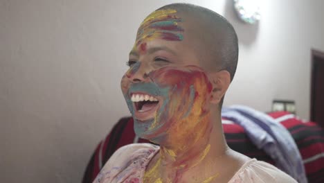 Happy-and-hopeful-cancer-patient-bald-girl-applies-colored-powder-on-cheeks-at-home-on-Holi-and-laughs