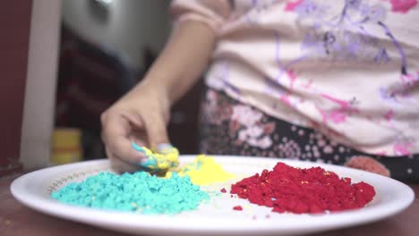 Hand-of-girl-playing-with-color-powders-on-plate-inside-home-due-to-coronavirus-lockdown,-slow-motion