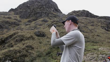 Young-caucasian-male-takes-photos-on-phone-at-Dead-Woman's-Pass-on-Inka-Trail-in-Peru-in-slow-motion