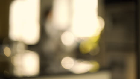 Woman-Walks-Into-Kitchen,-Rack-Focus-to-Soft-Focus-and-Bokeh