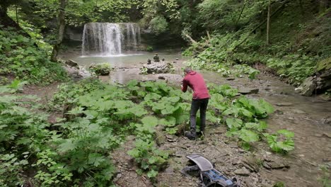 Wide-angle-shot-with-a-photographer-walking-through-the-low-plants-finding-a-composition-with-a-waterfall-in-the-background