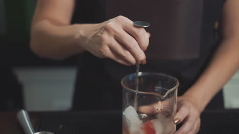 Speakeasy-bartender-making-cocktail,-stirring-liquor-with-bar-spoon