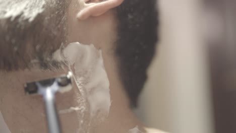 Close-up-white-man-shaving-off-his-beard,-bathroom,-static-shot