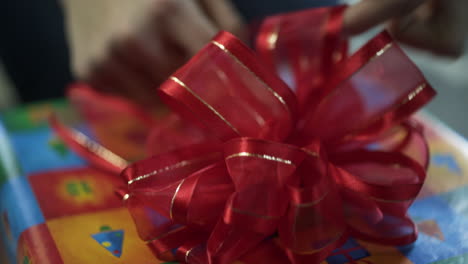 Woman-Placing-Red-Bow-on-Wrapped-Christmas-Gift,-Close-Up,-Handheld