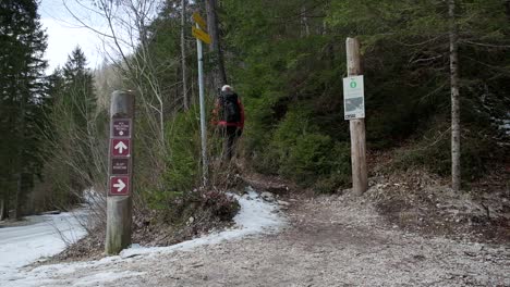 Man-walking-up-a-hiking-trail-towards-a-waterfall-with-a-backpack-on-and-a-red-jumper