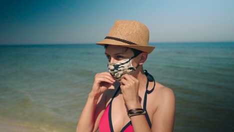 Young-woman-in-pink-bikini-enjoys-the-sun-at-the-calm-ocean-and-puts-face-mask-on