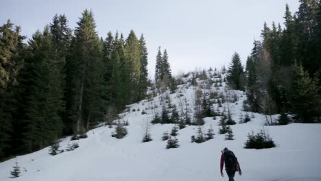 Hiking-up-the-side-of-mountain-in-deep-snow-with-a-backpack-and-clear-skies