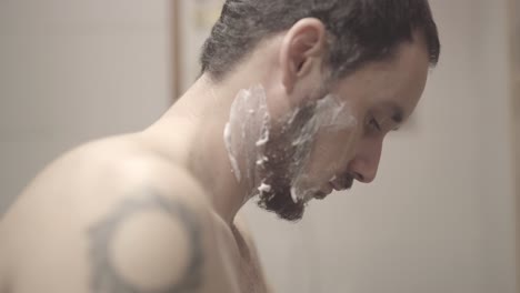 Close-up-man-shaving-off-his-beard,-bathroom,-static-shot