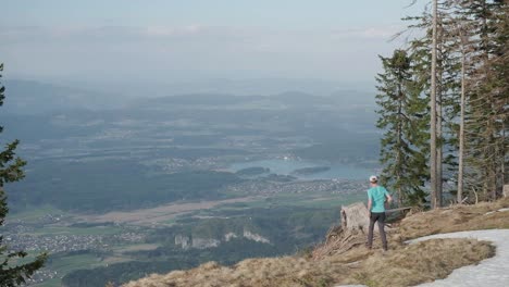 Running-down-to-a-tree-stump-to-celebrate-as-a-hiker-looks-over-Austria-and-the-city-of-Villach