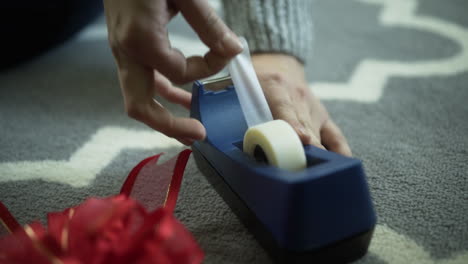 Woman-Pulls-Tape-From-Tape-Dispenser-to-Wrap-Holiday-Gifts,-Close-Up