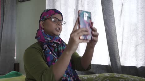 Chica-Asiática-Está-Triste-Y-Tratando-De-Tomar-Selfie-En-Casa-Usando-Un-Pañuelo-En-La-Cabeza,-Después-De-La-Quimioterapia