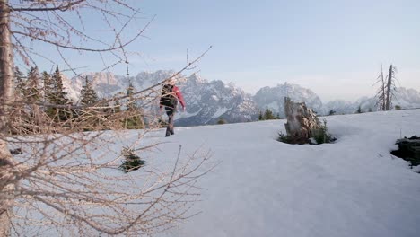 Hiker-walking-away-from-the-camera-toward-the-Julian-alps-with-the-ground-covered-in-Snow