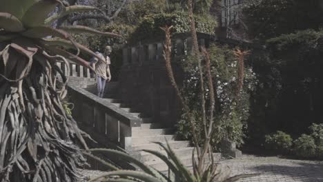 Traveler-with-backpack-walking-down-the-stairs-in-public-park,-summer,-Oporto,-Spain,-static-shot
