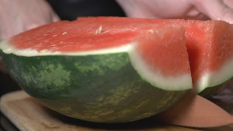 Hand-Holding-A-Knife-Cutting-The-Half-Sliced-Watermelon-Into-Two-Sections-Lengthwise---Closeup-Shot