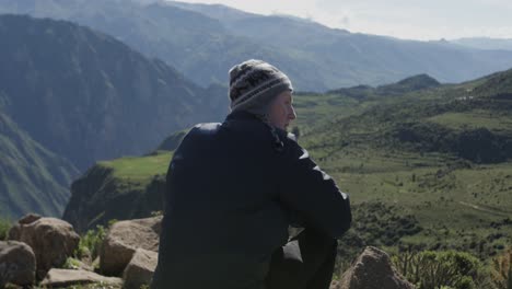 Caucasian-male-sitting-on-cliff-of-Colca-Canyon-in-Peru-and-enjoys-the-spectacular-scenary-over-the-canyon