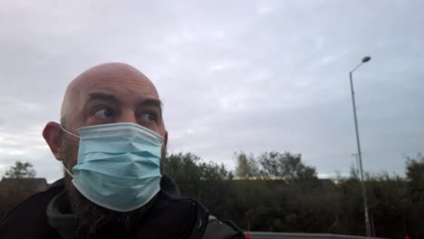 Male-in-workplace-wearing-uniform-and-PPE-face-mask-against-corona-virus-looking-around