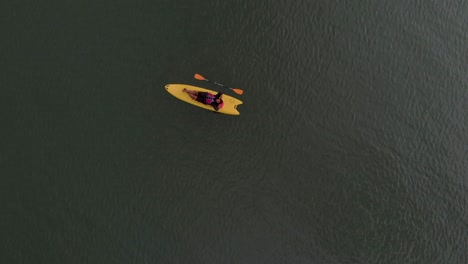 4k-Aerial-Top-Down-Drone-shot-of-a-28-year-old-Indian-male-relaxing-on-a-Kayak-in-the-backwaters-of-Varkala,-Kerala