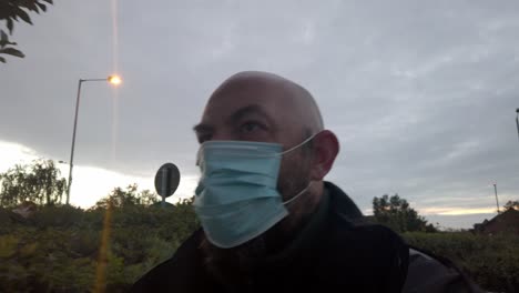 Male-in-workplace-wearing-uniform-and-PPE-face-mask-against-corona-virus-walks-under-tree