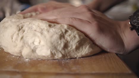 Baker's-Hands-Pressing-And-Kneading-Dough-On-The-Wooden-Board---close-up