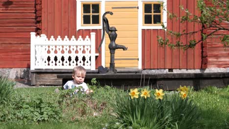 Junge-Sitzt-Im-Gras-Und-Blumenbeet,-Altmodischer-Nordischer-Garten