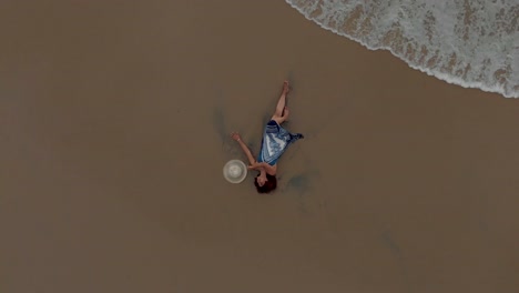 4k-Aerial-Top-Down-Drone-shot-of-A-pretty-27-year-old-young-Indian-woman-getting-drenched-by-the-sea-waves-along-the-shores-of-Varkala