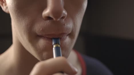 Man-Putting-The-Mouthpiece-Tip-Of-A-Vape-Pen-On-His-Mouth---Closeup-Shot