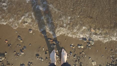 Sea-Waves-Splashing-To-A-Woman's-Feet-Standing-On-The-Stony-Shore---top-shot