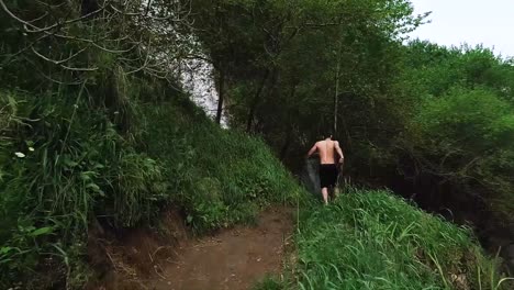 Young-Caucasian-man-runs-on-dirt-hiking-path-towards-Kfarhelda-river-and-waterfall