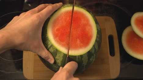 Cutting-The-Whole-Watermelon-Into-Half-Using-A-Kitchen-Knife-Placed-On-A-Wooden-Chopping-Board---High-Angle-Shot