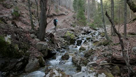 Camera-from-the-side-in-the-river-stream-as-the-hiker-walks-past-the-camera-away-from-the-camera-up-the-hil