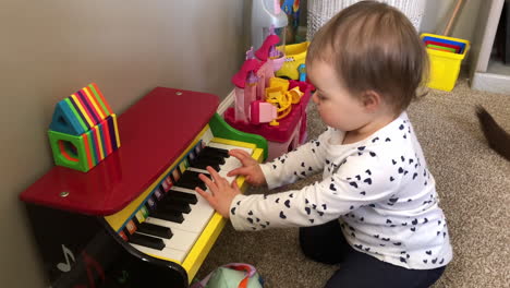 A-home-movie-style-video-clip-of-a-little-girl-playing-a-toy-piano-at-home
