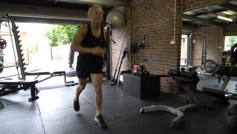 Tattooed-man-in-home-gym-split-jump-lunges-from-front