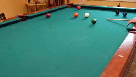 Man-Playing-8-Ball-Pool-Shoots-Several-Solid-Balls-into-Pockets-on-a-Brunswick-Table-for-Billiards-with-Green-Felt-in-Basement-of-Home,-Open-Bridge-Hand-and-Wooden-Cue-Stick,-Wide-Angle