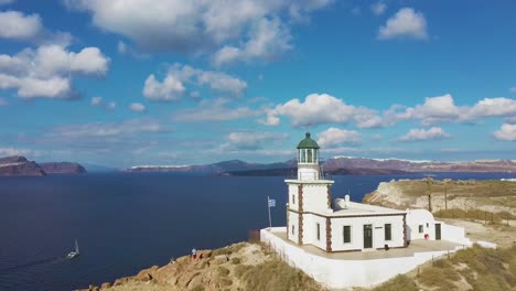 4k-Luftdrohnenumlaufbahn,-Die-Um-Den-Schönen-Leuchtturm-Santorini-Griechenland-Mit-Blauem-Himmel-Und-Wolken-Fliegt