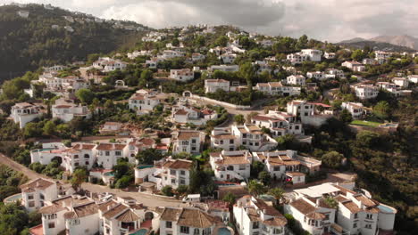 Orbit-aerial-4k-shot-of-small-town-mountains-white-houses-green-trees-day-cloudy-suburban-in-Pego,-Alicante,-Spain