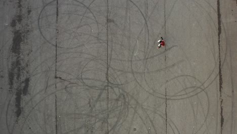 Birdseye-Aerial-View-of-Roller-Girl-Riding-Skates-on-Asphalt,-Top-Down-Drone-Shot