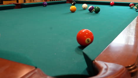 Man-Playing-8-Ball-Pool-Shoots-Several-Striped-Balls-into-Pockets-on-a-Brunswick-Table-with-Green-Felt-Missing-a-Shot-at-the-End,-Open-Bridge-Hand-and-Wooden-Cue-Stick,-Low-Angle