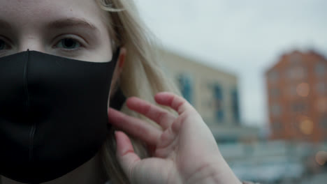 Blonde-young-woman-putting-on-black-face-mask,-close-up-in-slow-motion