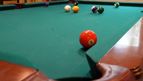 Man-Playing-8-Ball-Pool-Shoots-Several-Solid-Balls-into-Pockets-on-a-Brunswick-Table-with-Green-Felt-Missing-a-Shot-at-the-End,-Open-Bridge-Hand-and-Wooden-Cue-Stick,-Low-Angle-no-faces