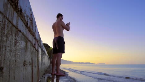 Shirtless-Man-Takes-Photos-With-Phone-At-Bang-Niang-Beach,-Khao-Lak,-Thailand