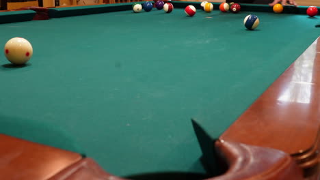 Person-Racks-8-Ball-Pool-Game-on-the-Spot-Gathering-Solid-and-Stripped-Billiard-Balls-on-Table-with-Green-Felt-and-Tightening-Rack-with-Hands-before-Lifting-Wooden-Triangle,-low-angle-no-faces