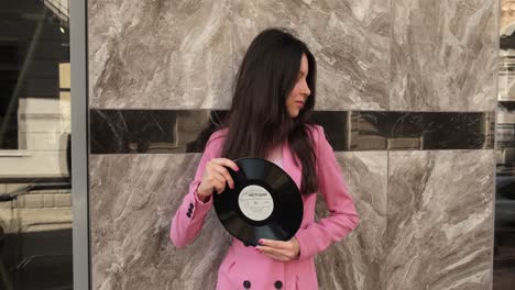 Stylish-brunette-in-pink-posing-with-two-discs-on-the-street