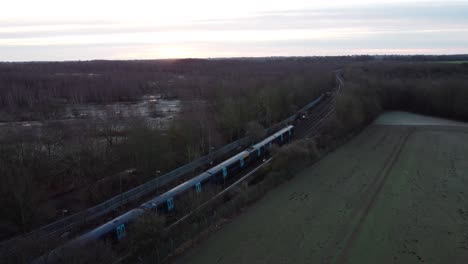 Drone-footage-of-a-train-leaving-the-station-with-a-sunrise-in-the-background