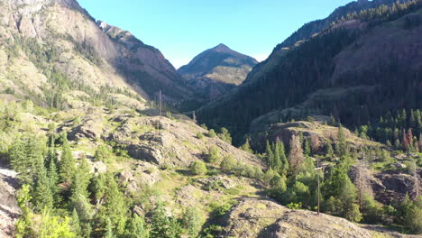Drone-Aéreo-En-Movimiento-Ascendente-De-La-Hermosa-Cordillera-De-Ouray-Colorado-Y-Senderos-Para-Caminatas-Rodeados-Por-Un-Espeso-Bosque-De-Pinos-Y-Líneas-Eléctricas-En-Las-Montañas-Rocosas