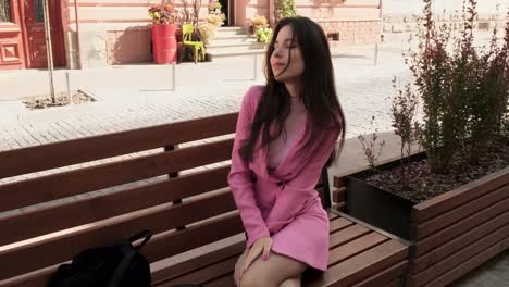 Young-model-in-pink-posing-on-a-bench-in-the-city