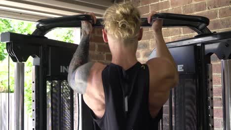 Muscly-man-in-home-gym-exercising-chin-ups-from-behind