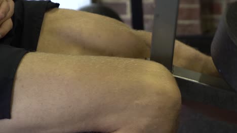 Muscly-man-in-home-gym-exercising-close-up-from-side-single-leg-raise